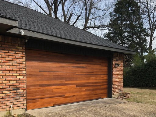 Modern wood-look residential garage door installed on a brick home