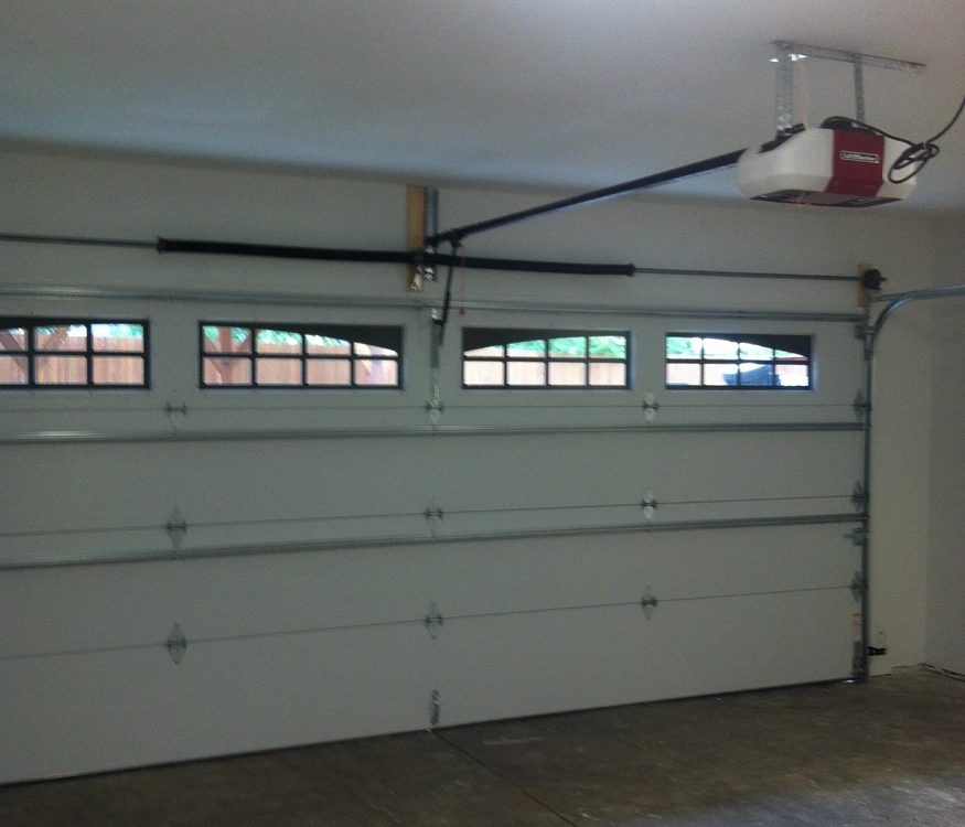 Residential sectional garage door with ceiling-mounted opener and torsion spring system