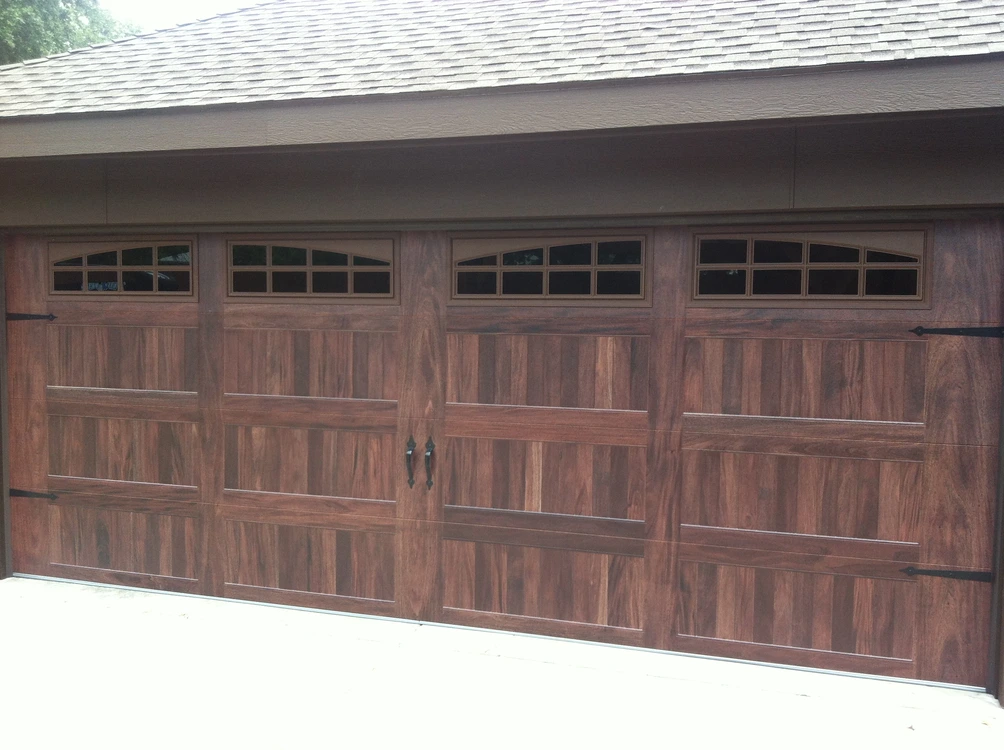 Modern wood-look residential garage door installed on a brick home